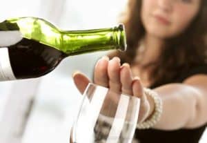 woman puts her hand over wine glass trying to stop drinking alcohol