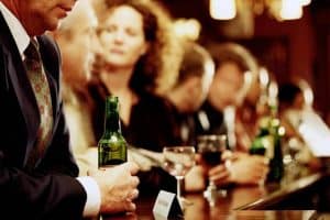 professional looking male drinking a bottle of beer in a pub