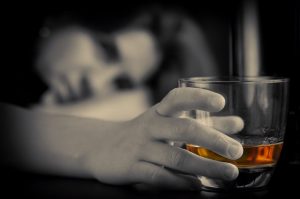 A woman suffering from alcohol dependence drinks from a glass, despite the negative long-term effects of alcohol on the brain.